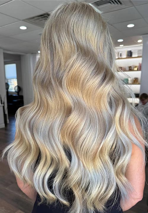 Long wavy blonde hair with soft highlights in a salon setting