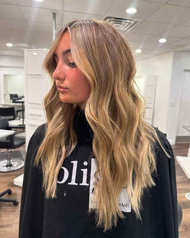 A woman with long blonde hair receiving a hair treatment at Elavína Salon and Spa in Manchester, NH.